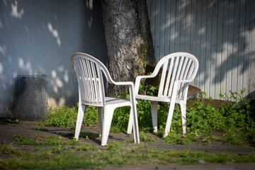 two plastic garden chairs under a tree