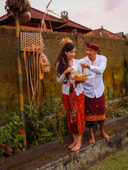 Traditional Balinese ceremony. Multicultural couple making Hindu religious ceremony with god's offerings. Culture and religion. Caucasian wife and Balinese husband. Penglipuran, Bali