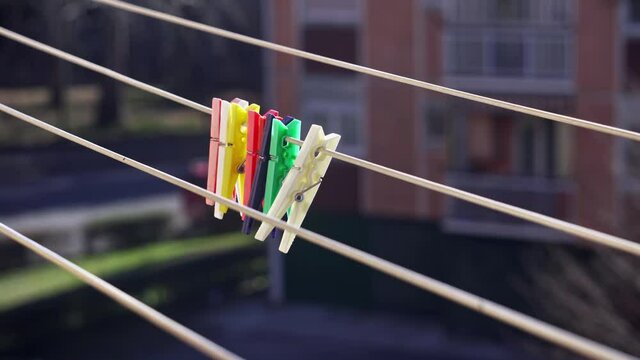 Close-up of colorful clothespins swaying in the wind against urban buildings