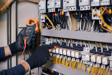 Electrician engineer work tester measuring voltage and current of power electric line in electical cabinet control.and wires on relay protection system. Bay control unit. Medium voltage switchgear.