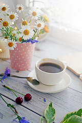 Coffee time. A cup of coffee on the table surrounded by books, flowers, berries. Romantic background with coffee cup, copy space