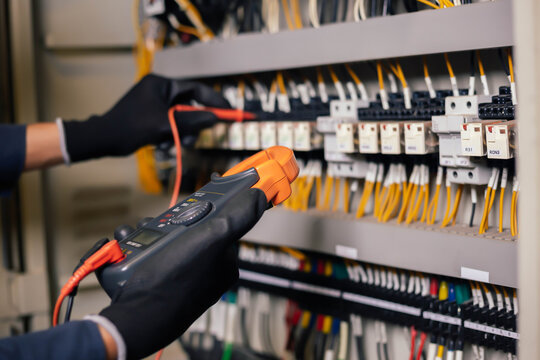 Electrician engineer work tester measuring voltage and current of power electric line in electical cabinet control.and wires on relay protection system. Bay control unit. Medium voltage switchgear.