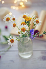 Small bouquet of wild flowers daisies in a glass vase on a wooden table. Summer background concept