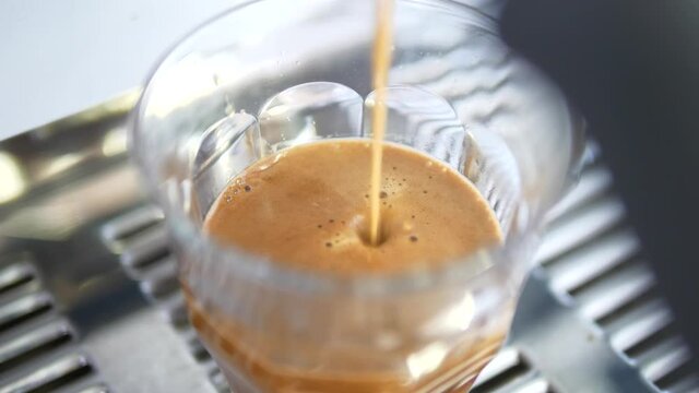 Pouring coffee stream from professional machine in cup. Barista making double espresso, using filter holder. Flowing fresh ground coffee. Drinking roasted black coffee in the morning