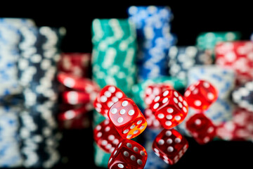 Stack of Casino gambling chips and red dices isolated on reflective black background