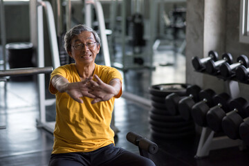 senior 60s smiling man stretching hands in gym