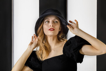 Portrait of a young pretty woman in a black hat and dress