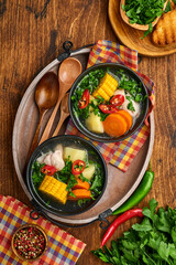 Chilean meat soup with pampkin, corn, fresh coriander and potatoes on old wooden table background. Cazuela. Latinamerican food.