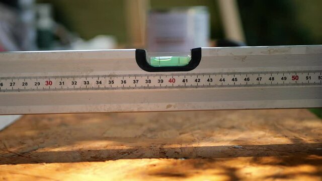 Spirit bubble level tool with ruler measuring the horizontal surface of plywood, close up