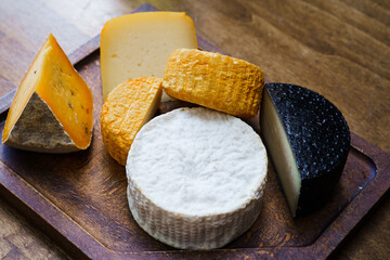 assorted cheese heads on cutting board on wooden table. cheese factory.