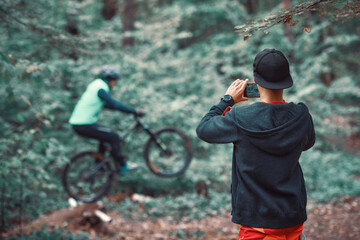 Moscow, Russia - Nov, 2018: MTB teacher helping rider learn to ride bicycle. Teaching a rider to ride a bike on a trail.  Two friends have fun in nature and representing concept of fitness on mtb bike