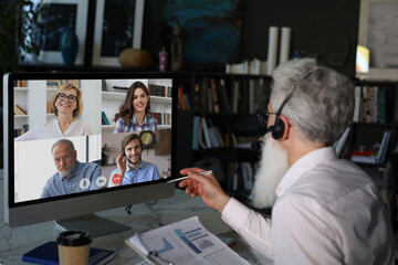 Businessman speak talk on video call with colleagues on online briefing during self isolation and...