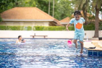 Little girl jumping into swimming pool.