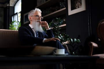 Thoughtful confident handsome businessman thinking while sitting on sofa in his modern office about business concept. Coffee break.