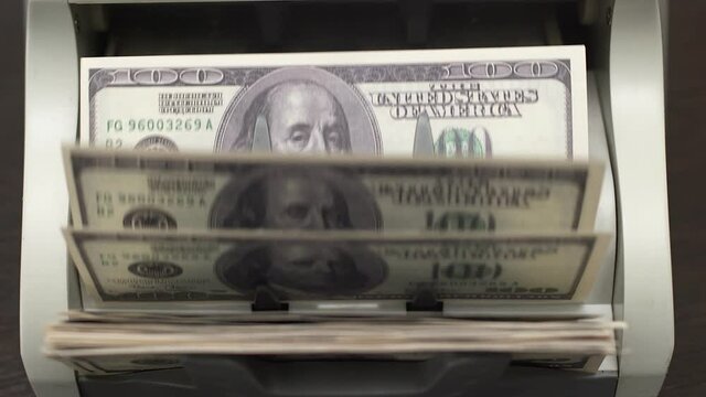 American dollars in cash. Bank transactions in closeup. Electronic counting machine for converting cash, calculating dollar bills, top view. Concept of wealth and the reasonable disposal of money