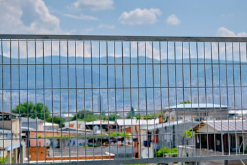 Obraz premium City behind the metal fences at during sunny day. Bursa city view from lowland to ulu mountain (uludag) and many lights beyond the fences.
