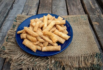 Closeup of Salted Namak Para or Nimki Indian Crunchy Savoury Snack in a Blue Plate with Burlap Fabric Isolated on Wooden Background
