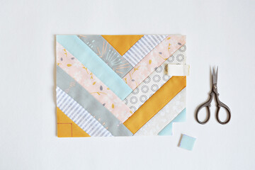 Working process: patchwork bag outer and embroidery scissors on white background	