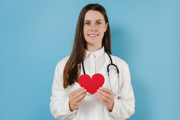 Portrait of friendly smiling young female doctor in professional medical white uniform with...