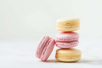 Stack of yellow and pink macaroons with shallow depth of field on the white background.