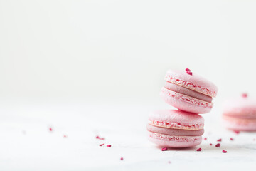 Pink macaroons with shallow depth of field on the white background. French sweet dessert cookies with red petals.