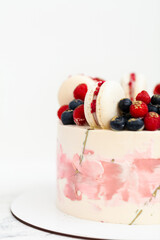 Birthday or anniversary cake with cream cheese frosting decorated with macaroons, blueberries and raspberries. Gold splash on the wedding cake.