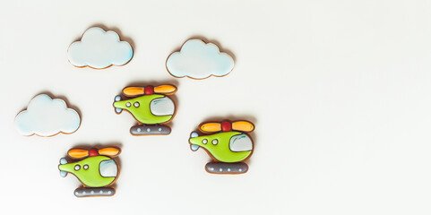 Gingerbread cookies in the shape of military helicopters flying in the clouds. Army or Men's day. Flat lay on white.