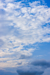 Fototapeta premium Scattered bright white clouds under the beautiful blue sky vertical view