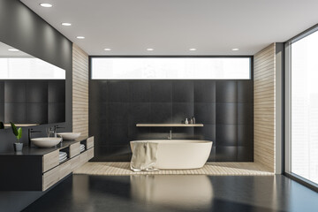 Beige bathtub in panoramic black bathroom interior with narrow window