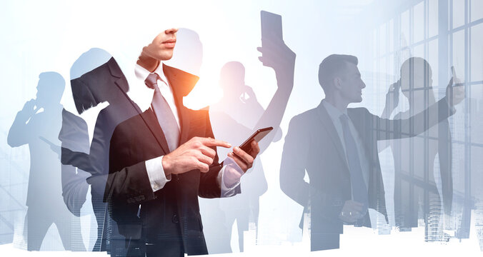 Silhouettes of busy business people contacting via smartphones at distance using different types of communications, double exposure. Panoramic office and New York skyscrapers on background