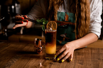 great view of glass with cold bumble coffee which woman decorates with mint leaf