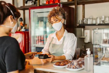Female business owner taking a card payment from a customer duri