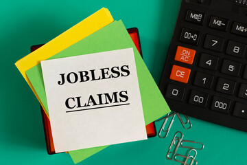 JOBLESS CLAIMS - words on note paper against the background of a calculator and paper clips.