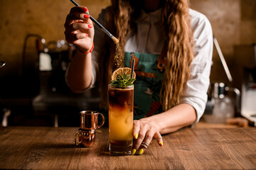 woman bartender holds brush and gently sprinkles seasoning on glass with cocktail