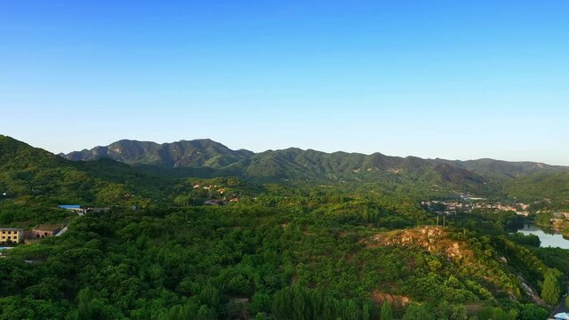 Drone flying over small villages among green mountains in the morning, aerial photography of natural landscape