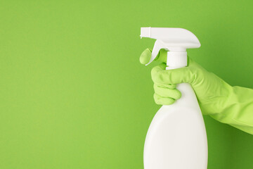 Profile photo of hand in green rubber glove using atomizer on white detergent spray bottle without...