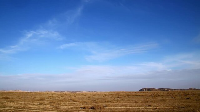 Field in winter and cirrus clouds in blue sky, time-lapse