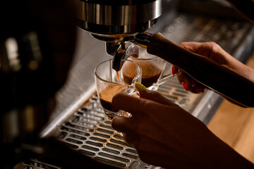 Professional espresso machine is pouring hot coffee into a neat clear cups
