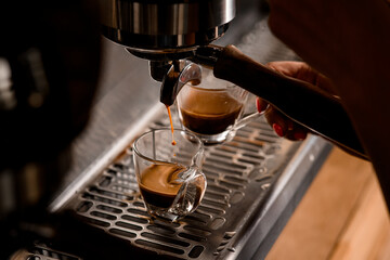 close-up of stream of hot coffee flowing from an espresso machine into cup