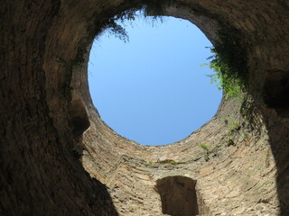 round window to the blue sky from a stone tower, the tower is overgrown with grass