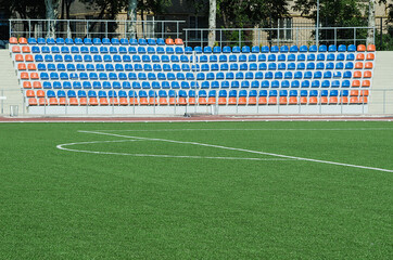  Grass field and plastic seats at stadium, open door sports arena.