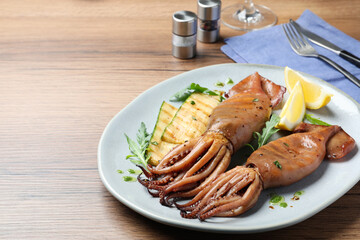 Delicious grilled squids served on wooden table, space for text