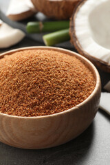 Natural coconut sugar in wooden bowl on grey table, closeup
