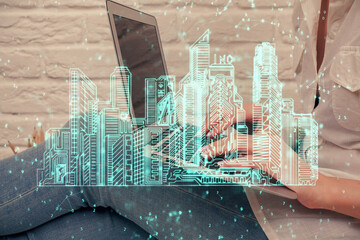 Double exposure of woman hands typing on computer and buildings drawing. Smart-city concept.