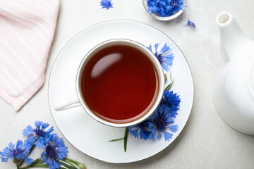 Composition with tea and cornflowers on light table, flat lay