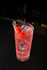 bartender special cold pink fruit punch cocktail wine or mocktail with cherry pop juice in tall glass goblet on black background luxury hotel pub iced beverage menu