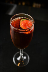 bartender special cold red wine cocktail or mocktail fruit juice with strawberry in tall glass goblet on black background luxury hotel pub iced beverage menu