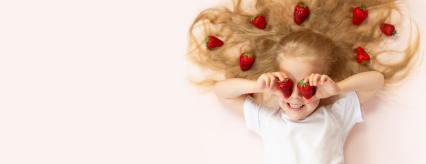 Banner with a beautiful little girl with strawberries on a pink background. Horizontal orientation, copy space.