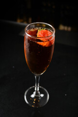 bartender special cold red wine cocktail or mocktail fruit juice with strawberry in tall glass goblet on black background luxury hotel pub iced beverage menu