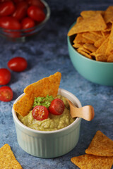 Homemade guacamole with corn chips and cherry tomatoes	